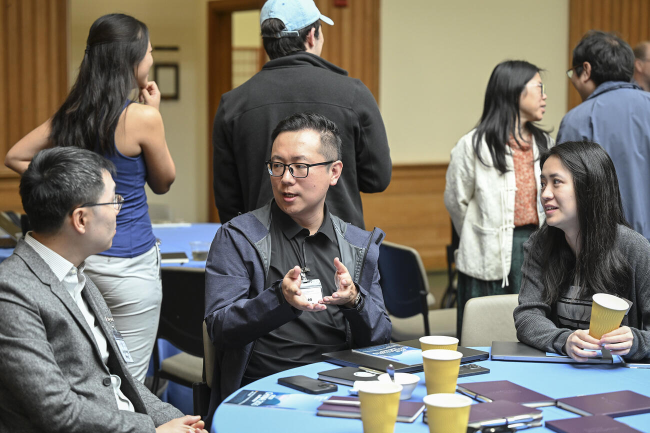 Three people sit at a table and talk animatedly. 