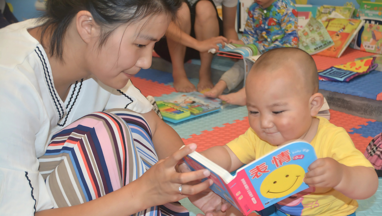 A caregiver reads to a baby.