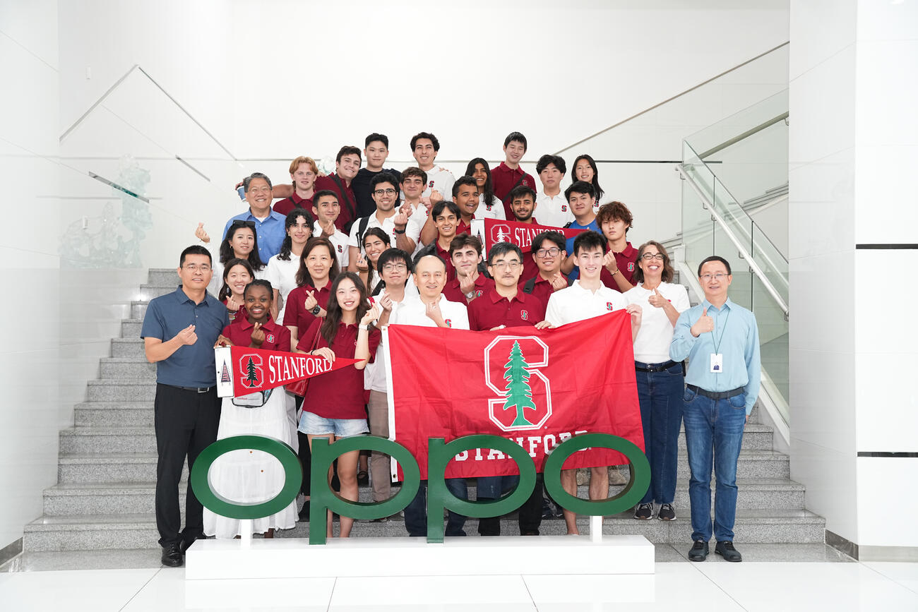 Group photo of students, staff, and faculty in China with Stanford flag. 