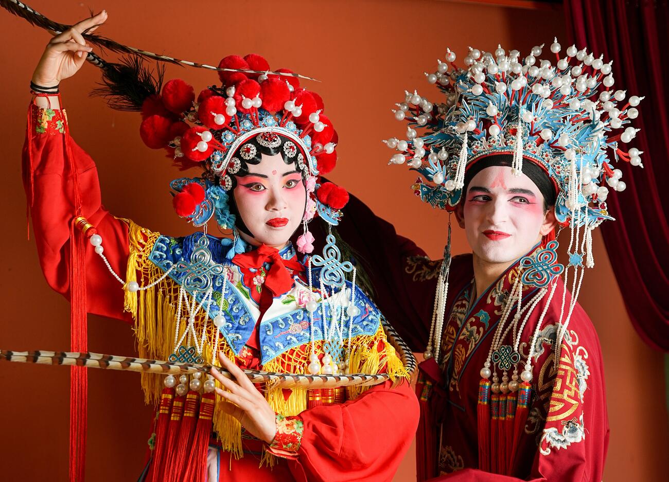 Two students dress up in Chinese opera attire and makeup and pose.