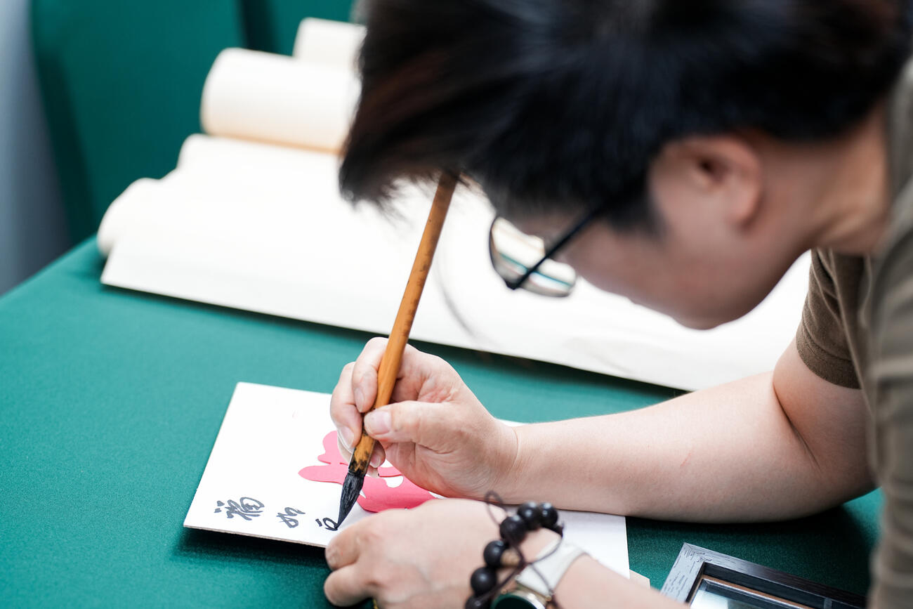 Close up of a student doing brush calligraphy in Chinese.