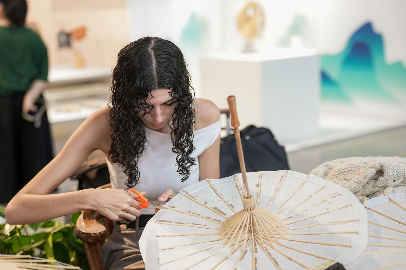 A young woman makes a paper umbrella. 