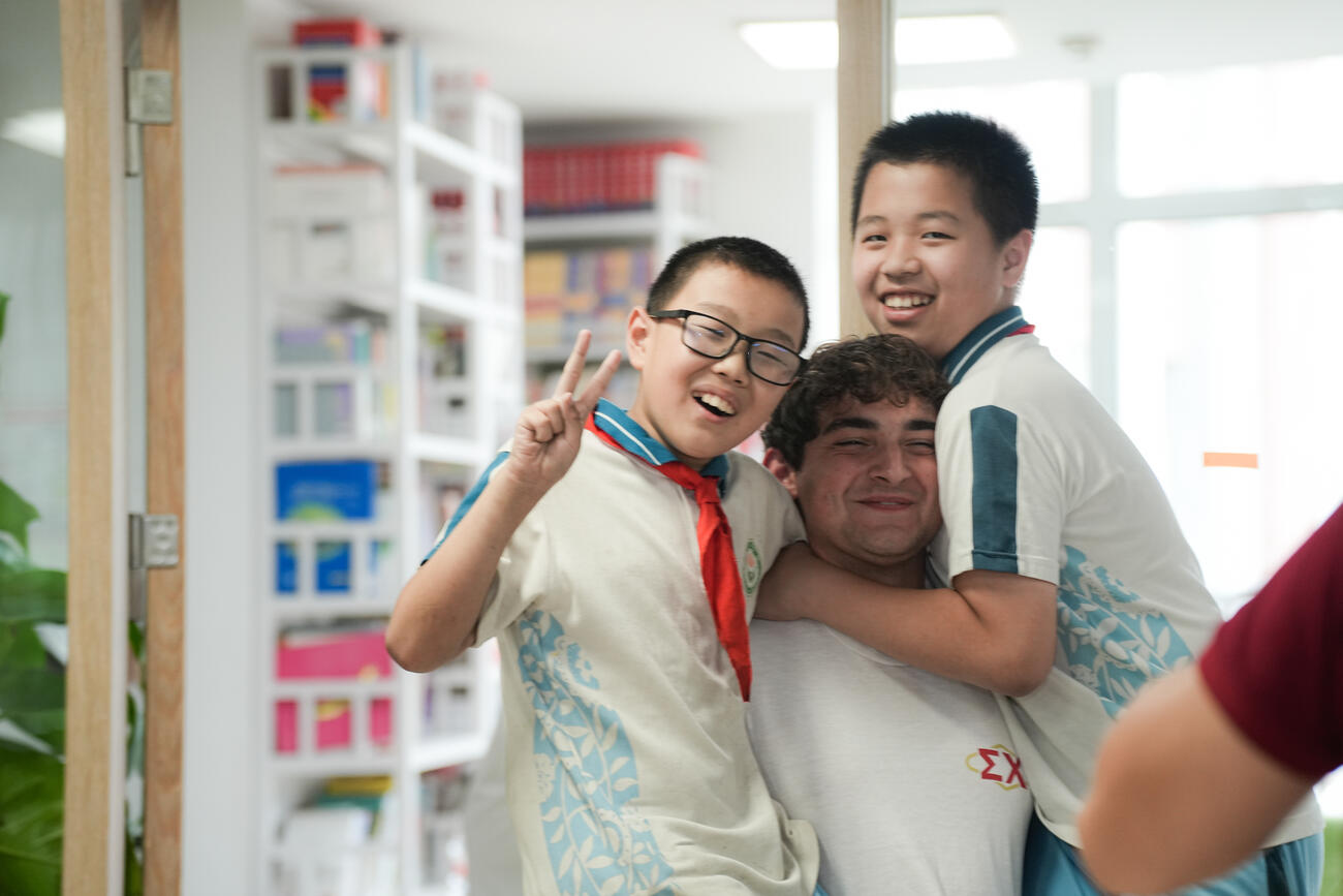 Two young school children hug an older student.