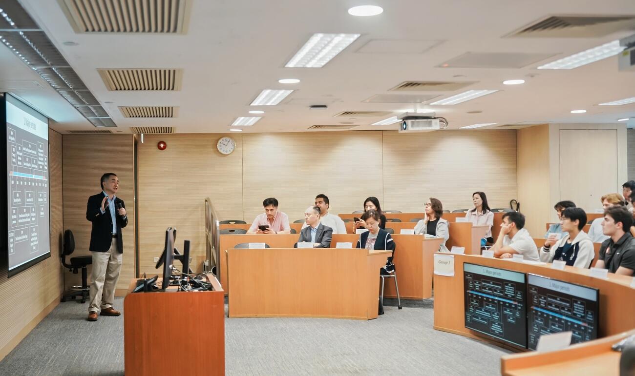 A professor lectures a group of students in a classroom.