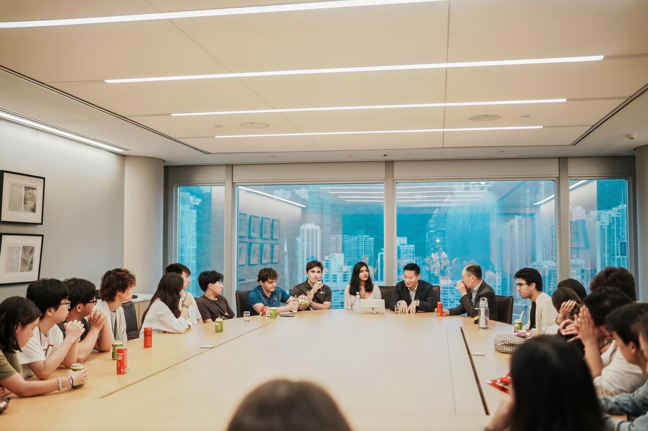 Students sit around a large boardroom. 