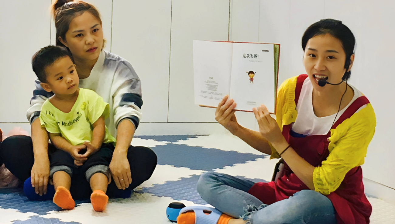 A staff member at a parenting center reads a book aloud to a child and caregiver.