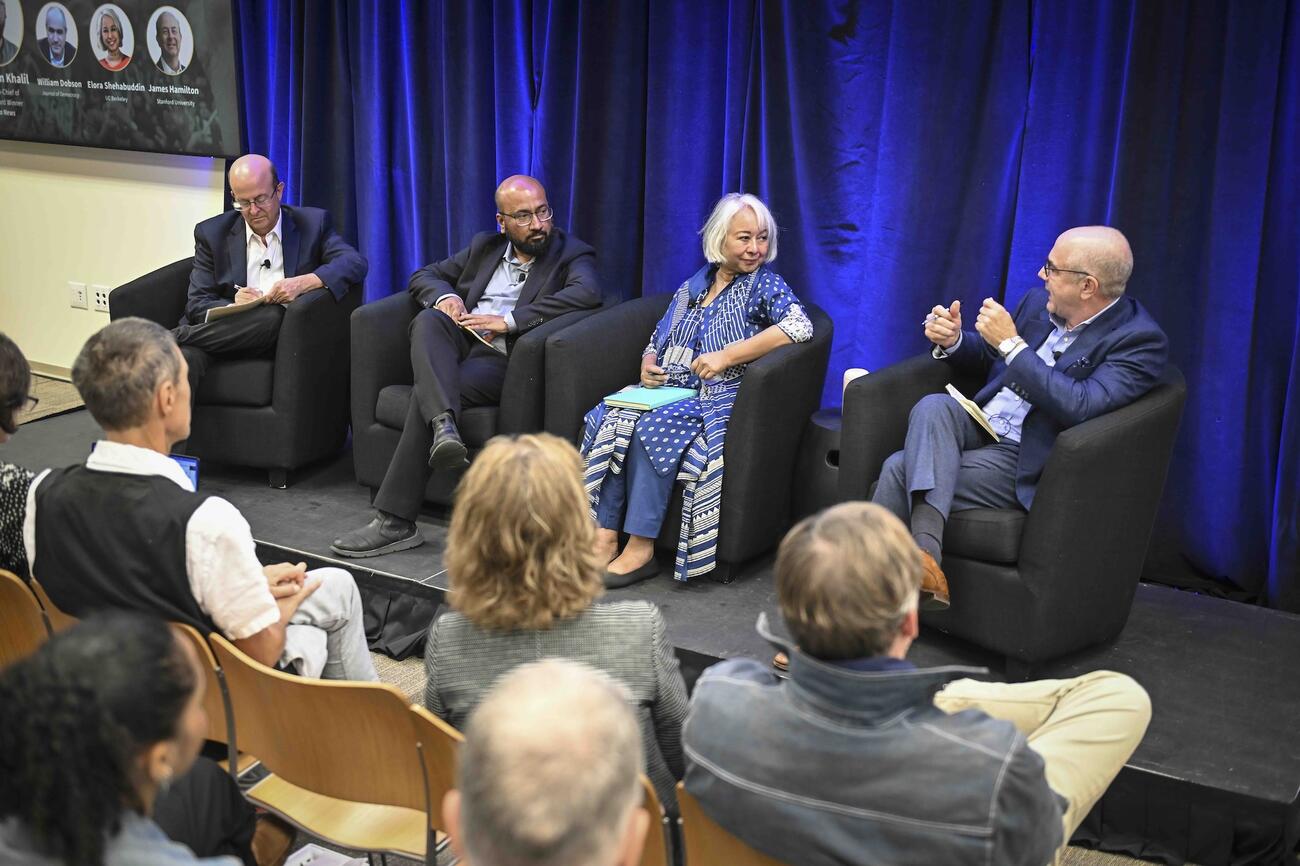 Four panelists seated on stage in a conference room having a discussion.