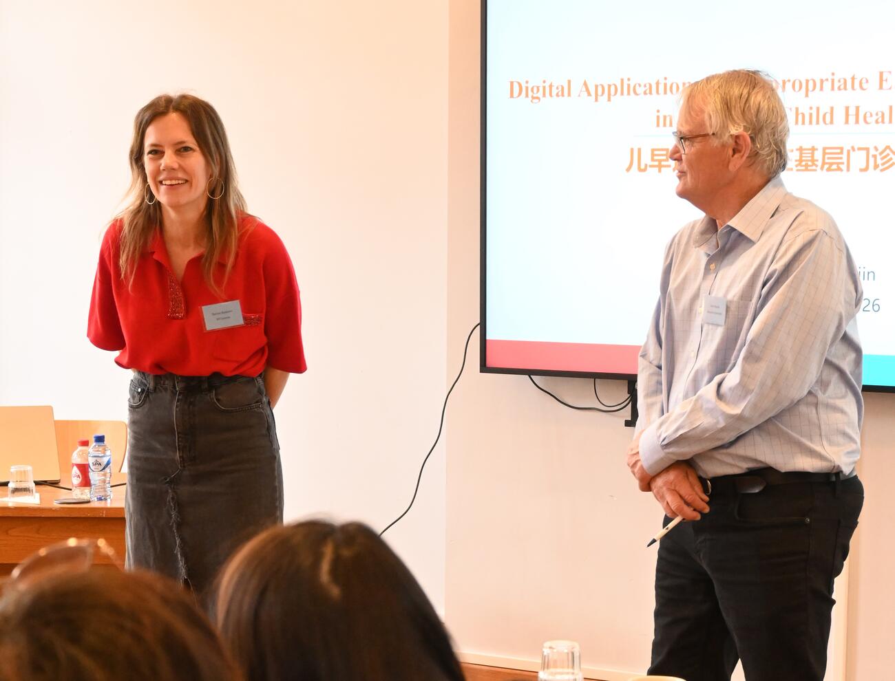 Dorien Emmers and Scott Rozelle deliver remarks at the front of a conference room.