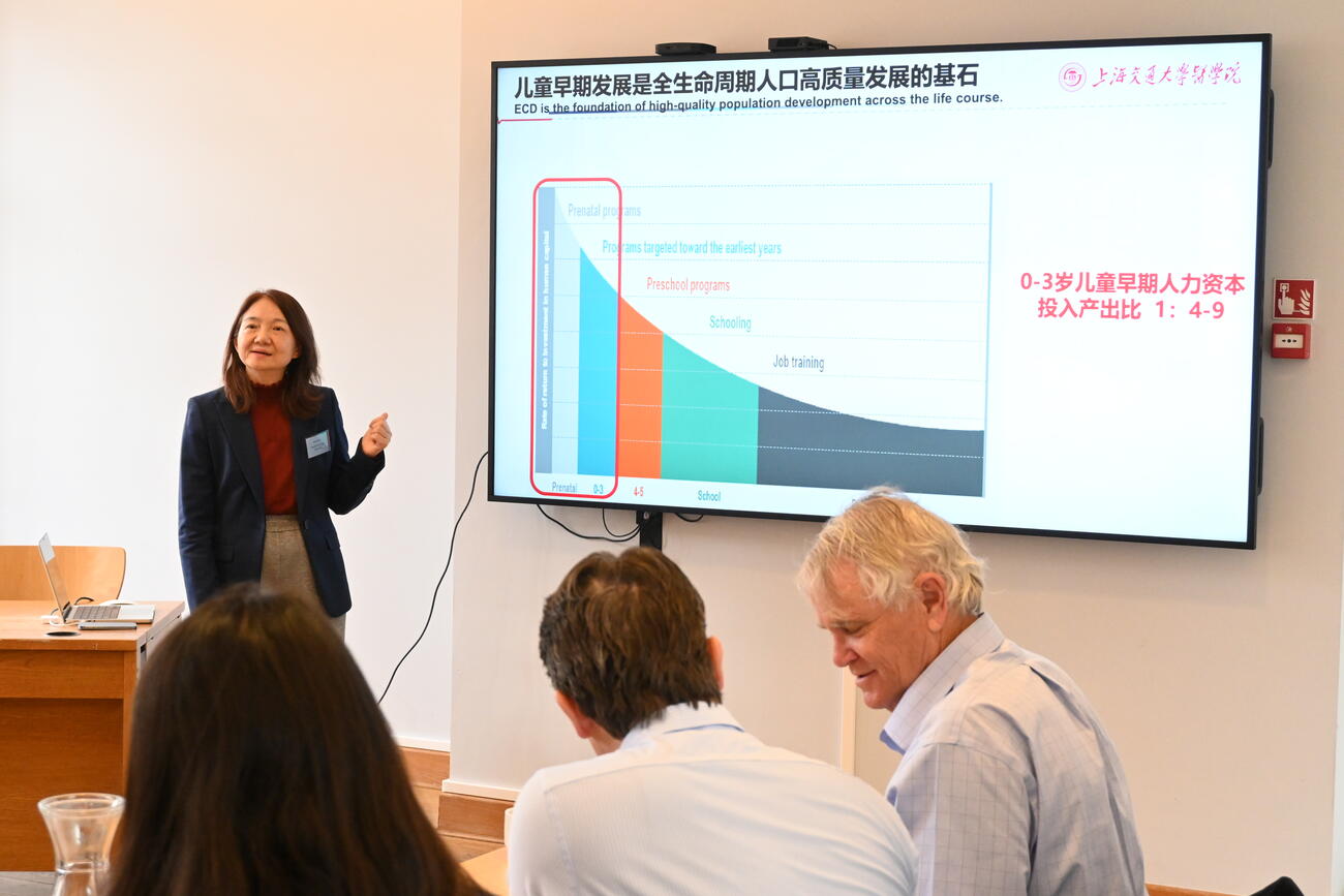 A woman presents data on a large screen in a conference room.