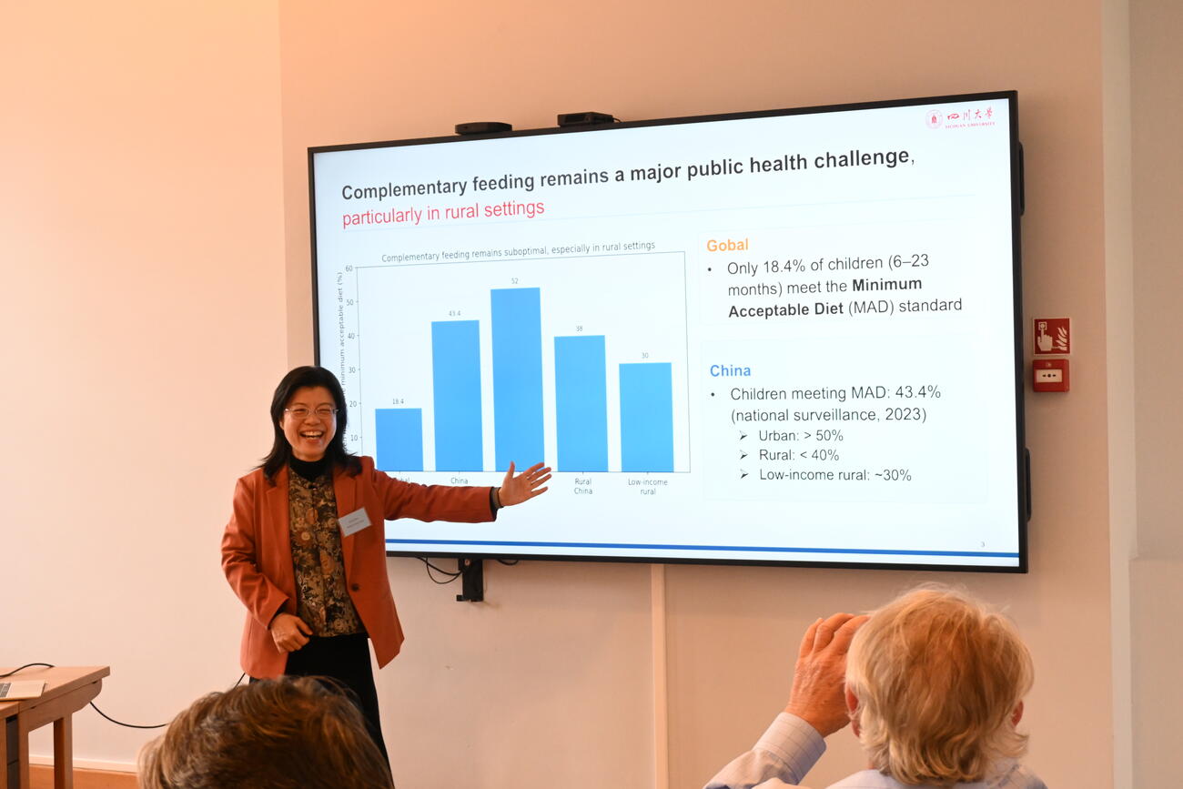 A woman presents data on a large screen in a conference room.