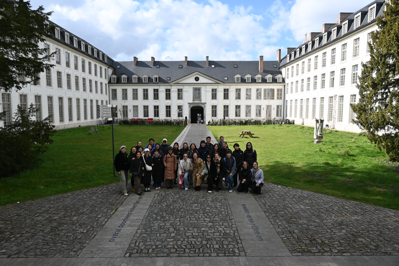 A group of conference attendees pose in a grand courtyard.