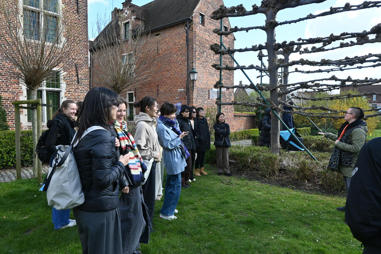 A group stands outside listening to a guide.