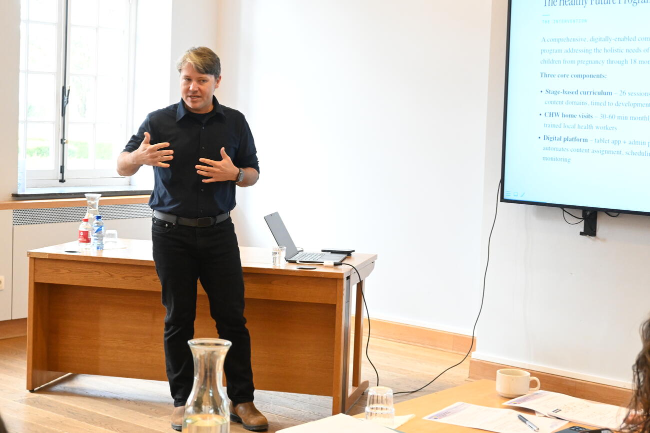 A man presents at the front of a conference room.