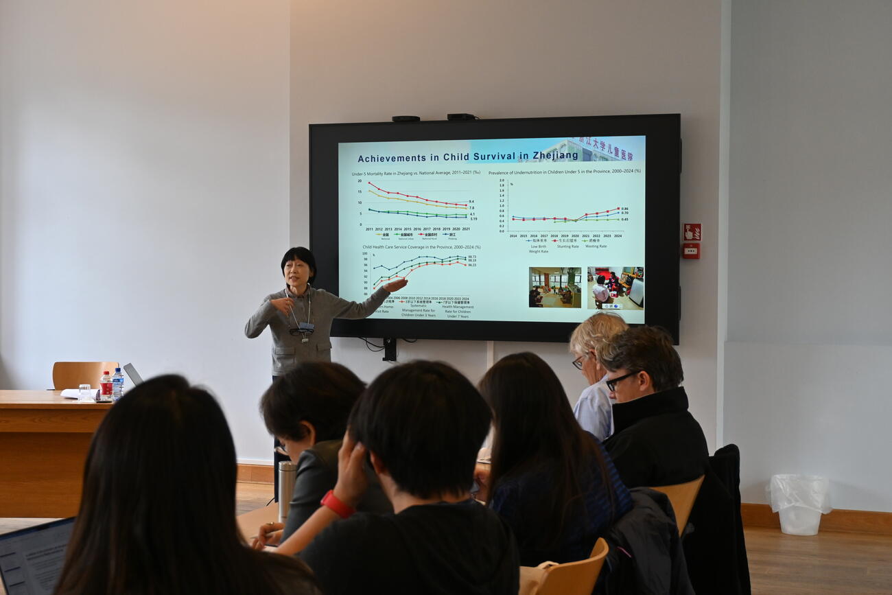 A woman presents data on a large screen in a conference room.