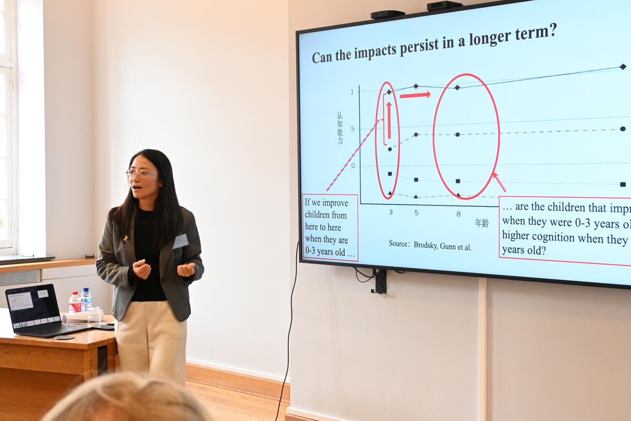 A woman presents data on a large screen in a conference room.