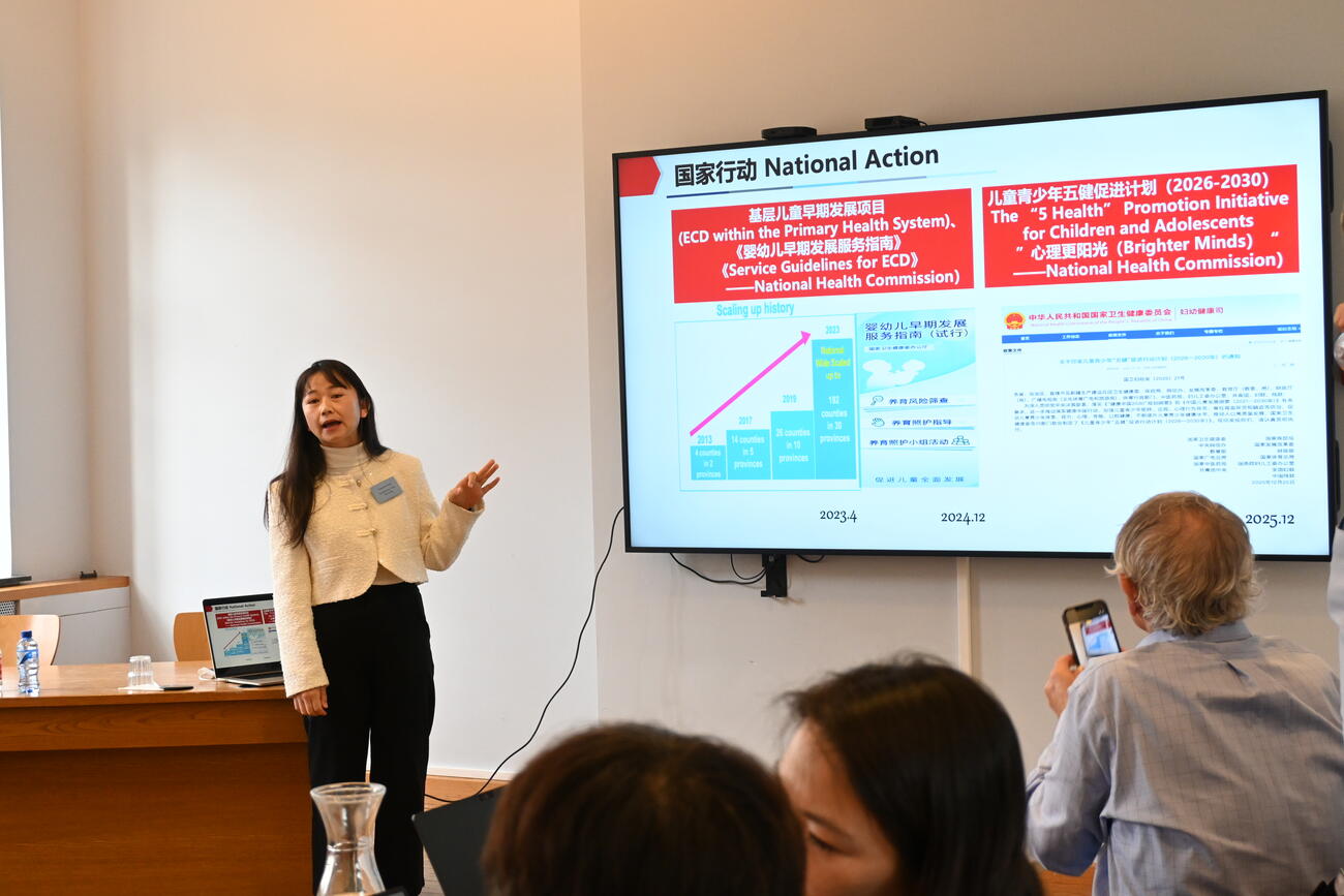 A woman presents data on a large screen in a conference room.