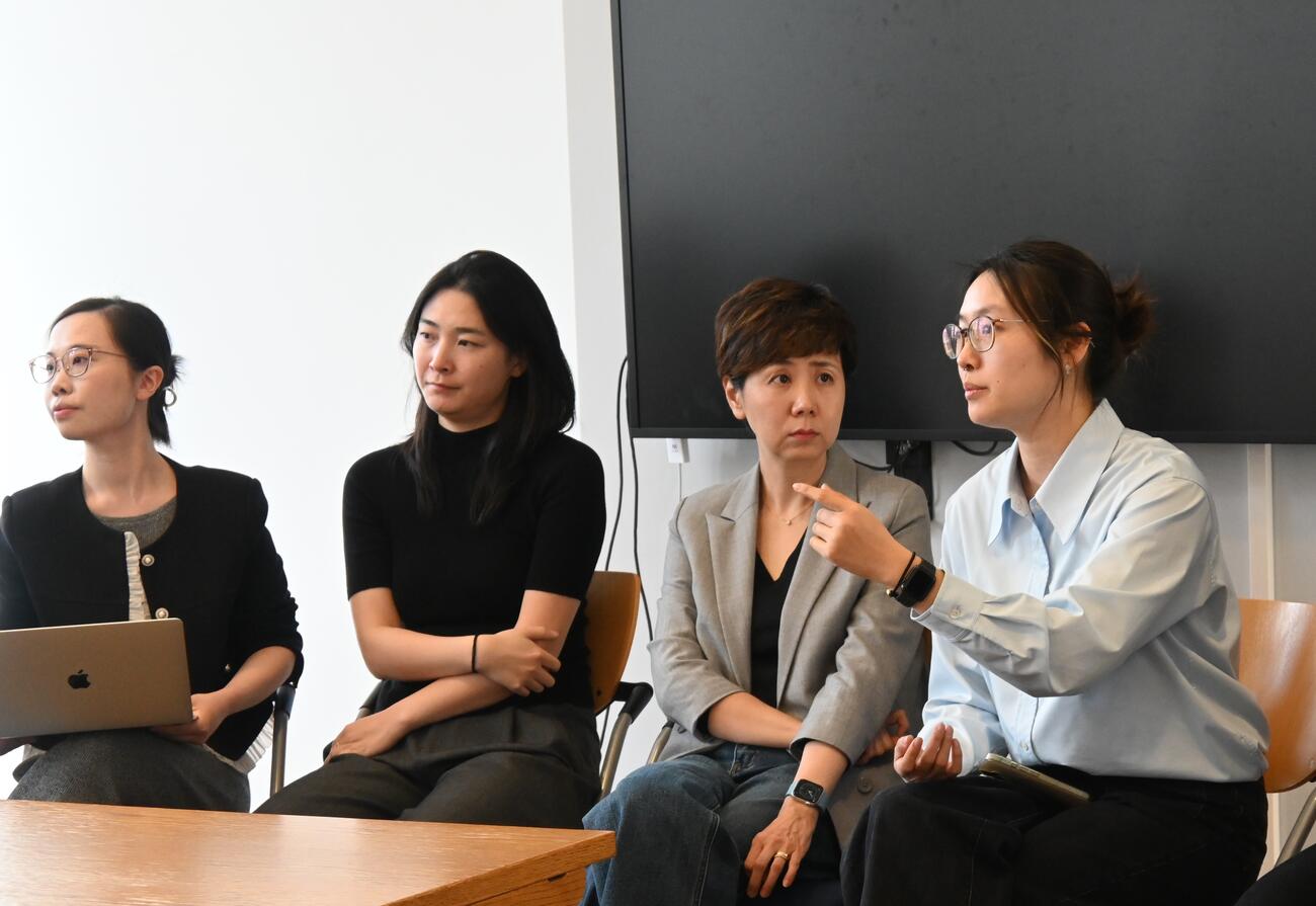A group of women sit in discussion in a conference room.