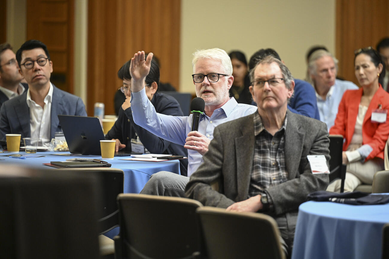 An audience member speaks into a handheld mic from an event audience.