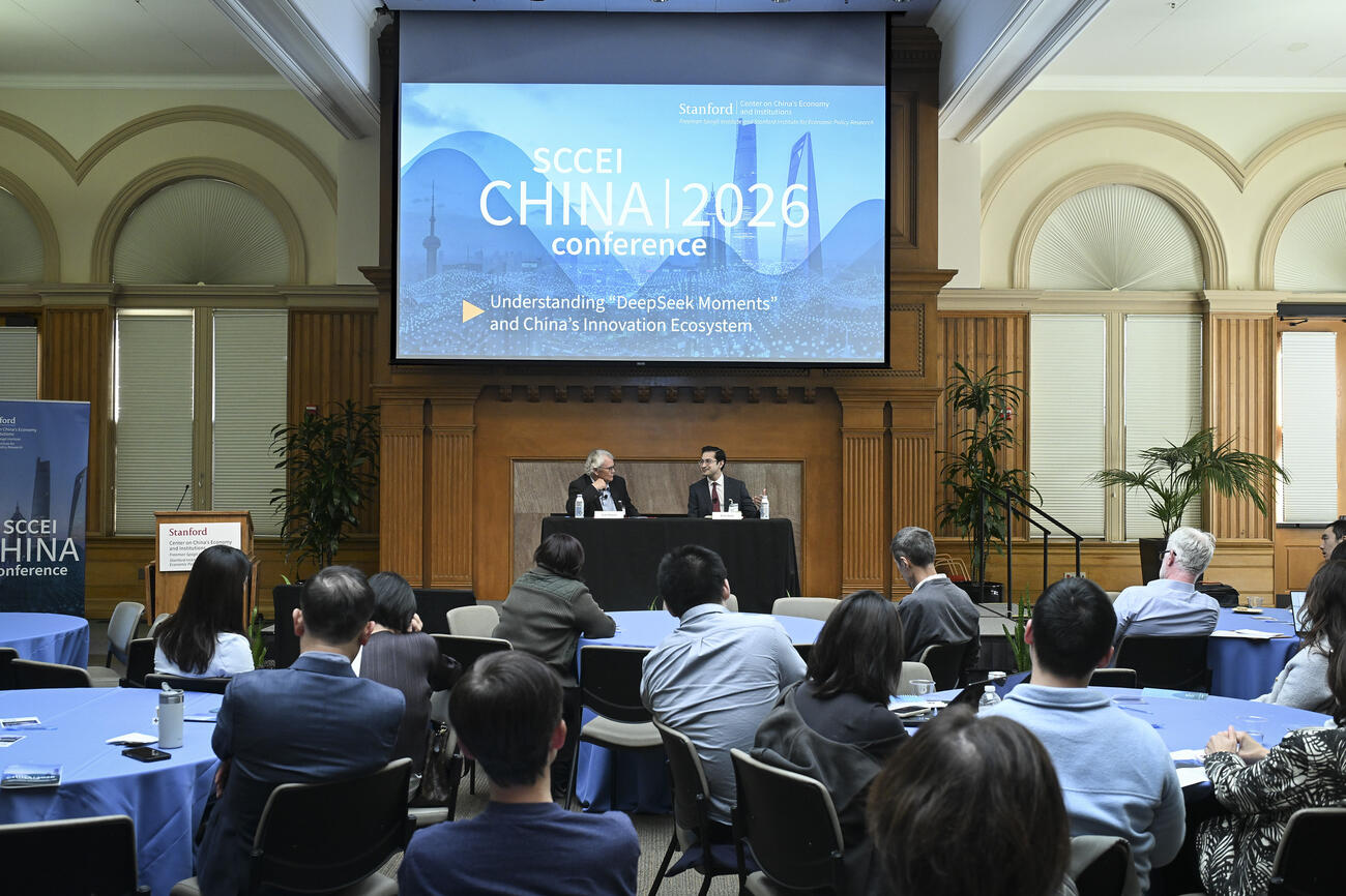 A full room of attendees seated at round tables during a conference. 