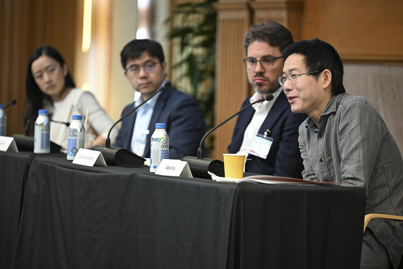 A group of people sit behind a table on a panel session at a conference.