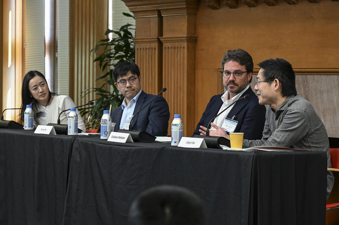 A group of four people sit at a table on stage during a panel discussion.