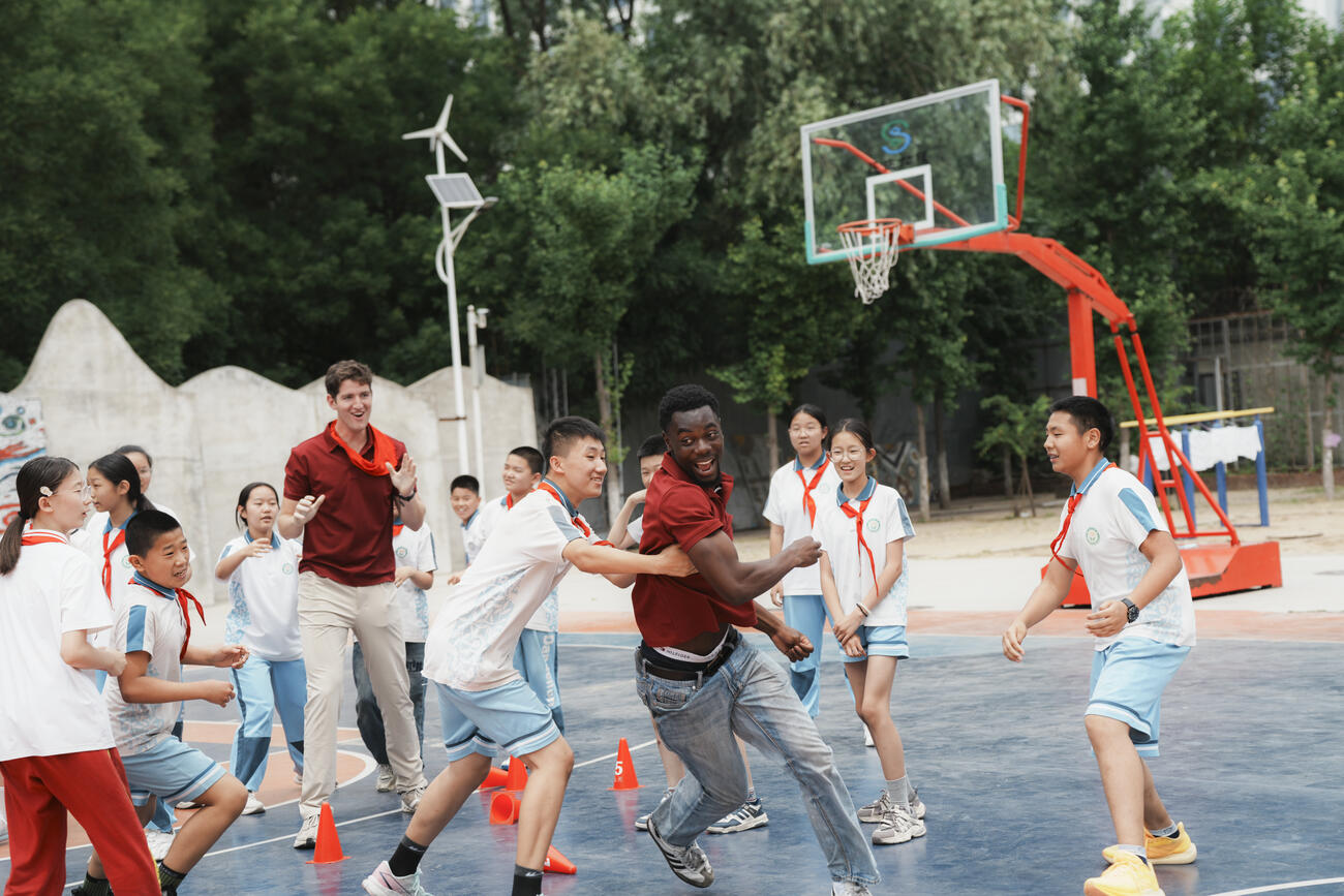 Kids play basketball outdoors.