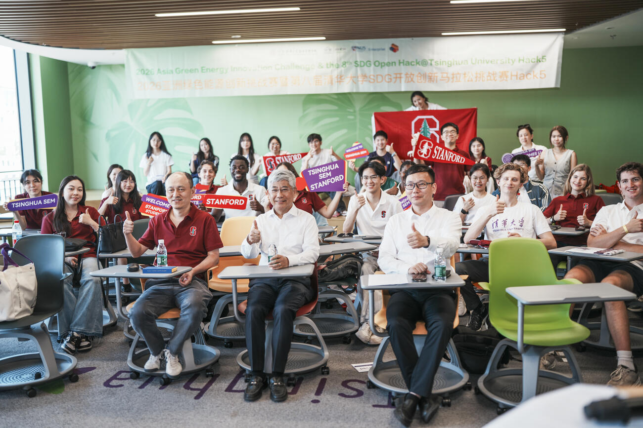 Students and teachers pose for a photo seated in a classroom.
