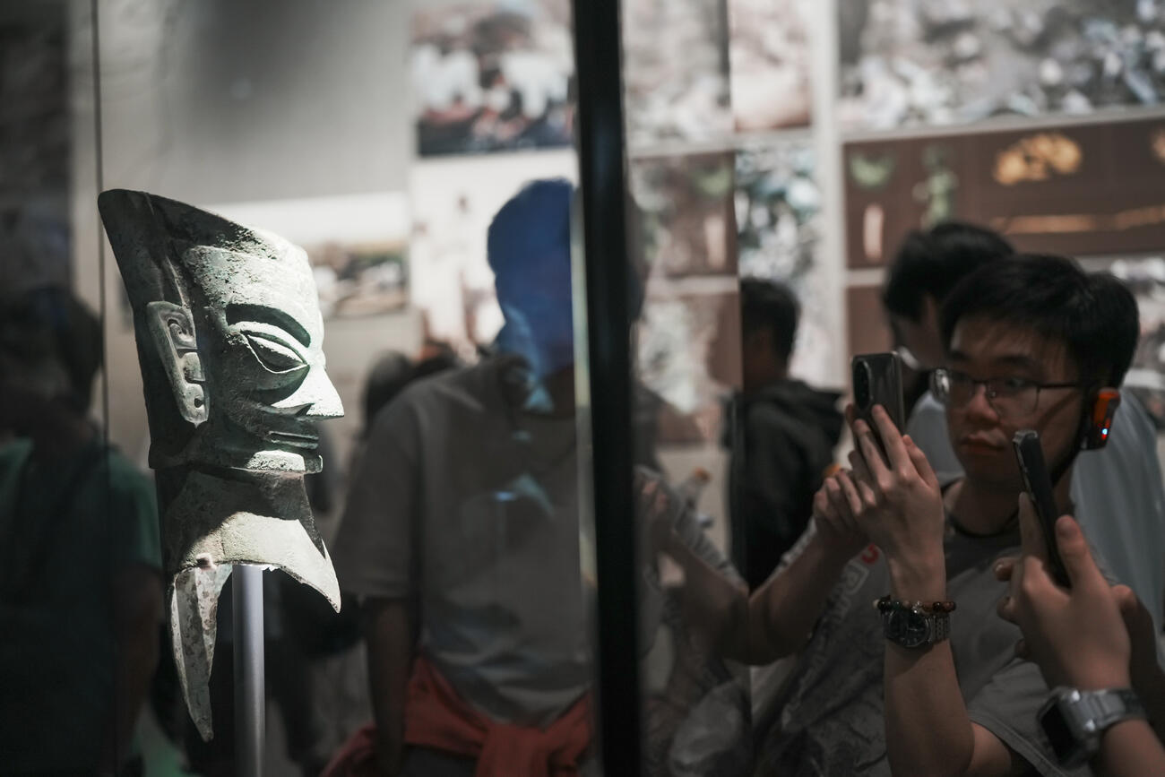 Students look at an ancient vase in a glass case.