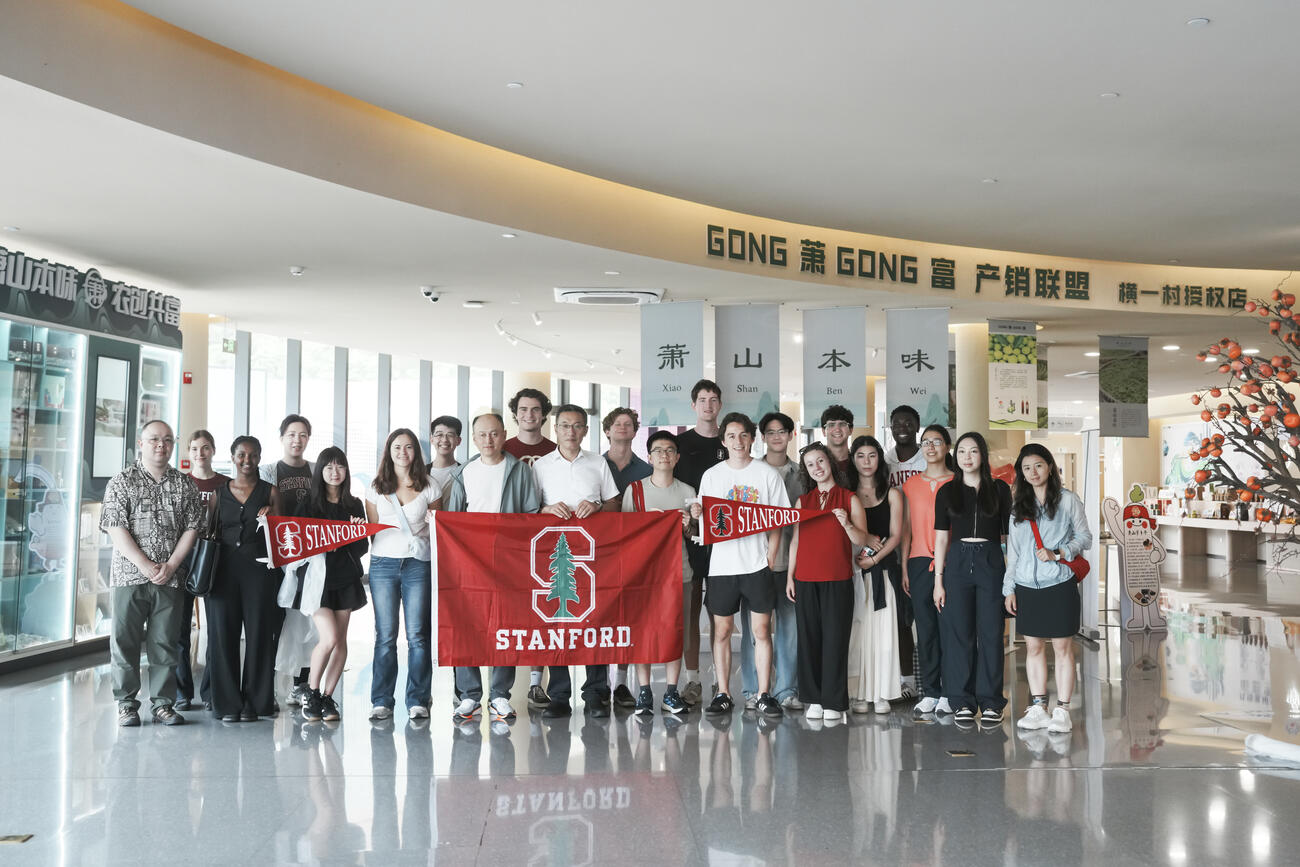 A group of students stand with a Stanford flag.