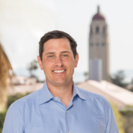 Jeff Decker smiles wit Hoover Tower seen in background