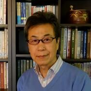Ke Wang poses in front of a bookcase.