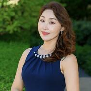 headshot of MIP student Elena Kim in a blue dress with a green natural background