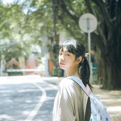 Girl with backpack stands on street in China.