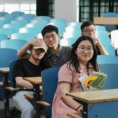 College students smile while sitting in an empty classroom. 