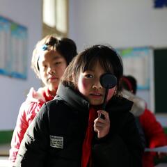 School girl stands for an eye exam in a classroom in rural China.