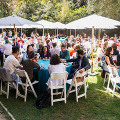 photo of crowd of people sitting at tables outside