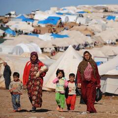 Syrian internally displaced people walk in the Atme camp, along the Turkish border in the northwestern Syrian province of Idlib, on March 19, 2013.