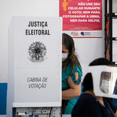 Image of voter wearing a face mask and voting in a booth