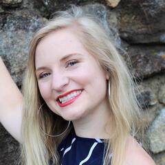 Mishaela is wearing bright red lipstick and has her head tilted to the side.