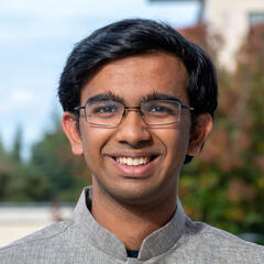 A closeup of Aditya's face. Aditya wears glasses and is smiling.