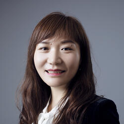 Tianli Feng wearing blazer standing in front of a background