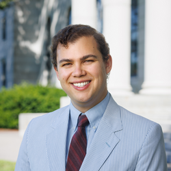 Andrew wearing a suit, posing before columns