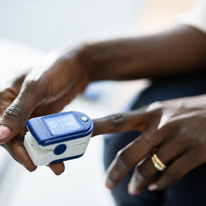 Photo of a dark-skinned woman using a pulse oximeter