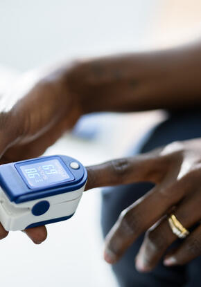 Photo of a dark-skinned woman using a pulse oximeter