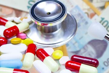 Close-up on coloured medication capsules and a stethoscope on the background of Korean won bills.