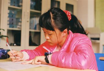A girl in China sits at a classroom desk taking a test. 