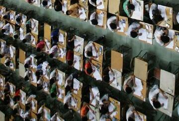 Students sit at separated desk while taking an exam.