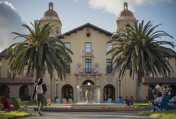 a fountain and two palm trees in front of a building