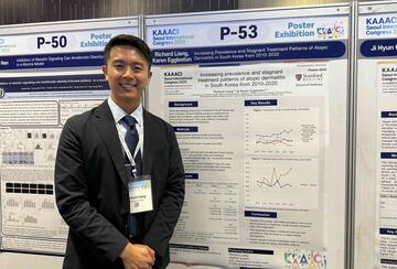 Richard Liang standing next to a poster presenting his research at a conference. 