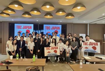 a group of students standing with signs, "TBC Japan"